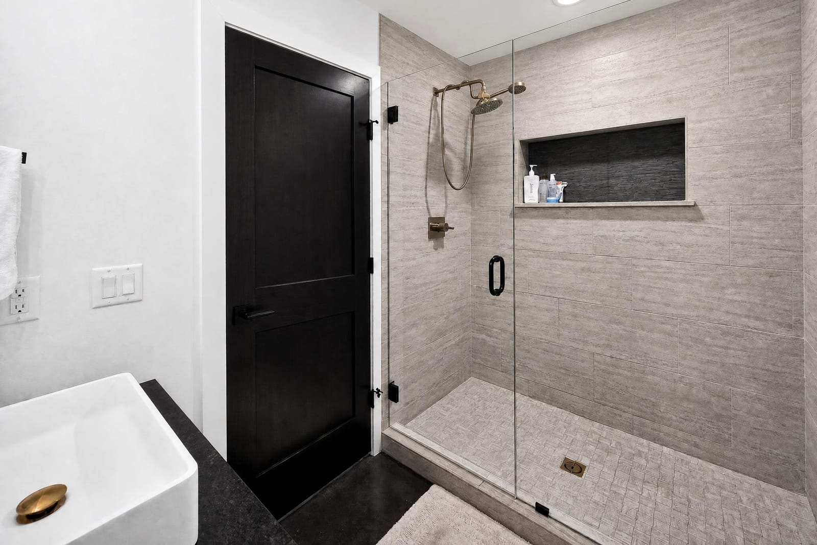 The en-suite shower behind glass, with a black door.
